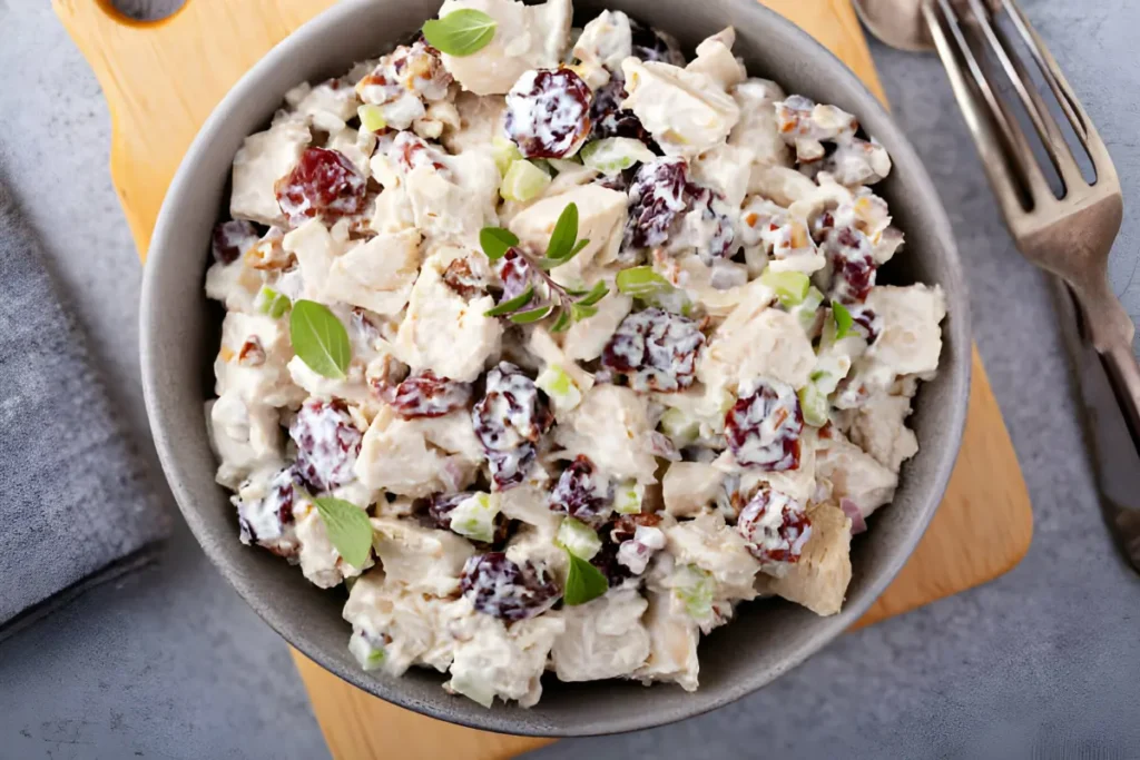 Chicken salad with dried cherries, almonds, and fresh greens in a white bowl