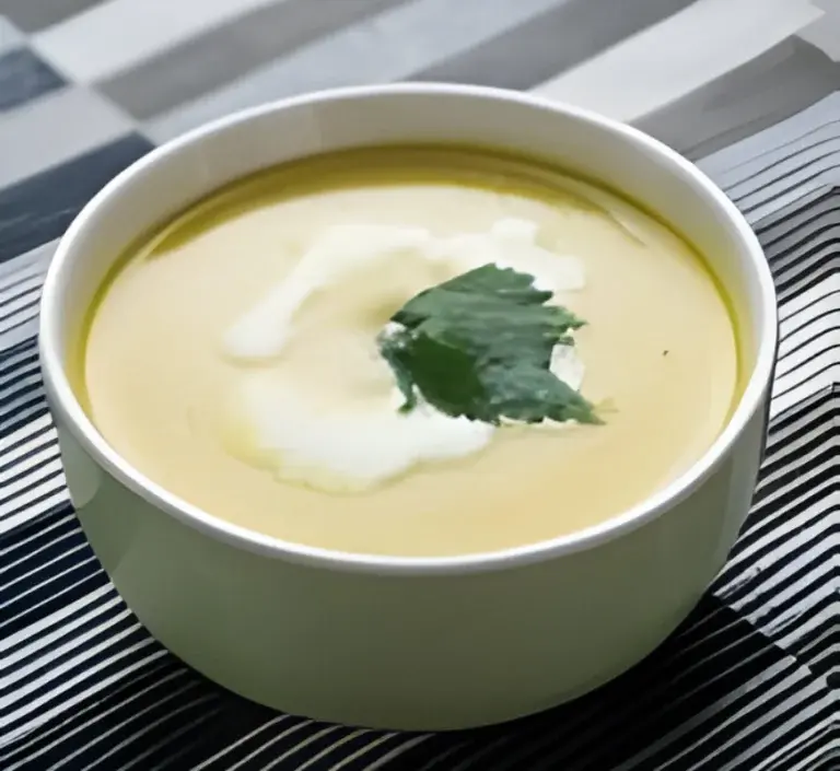 Steaming bowl of Poblano Cream Soup garnished with sliced poblano peppers and a dollop of cream, served on a rustic wooden table.